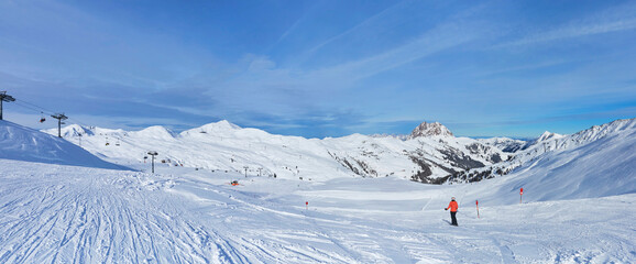Schönes Winterpanorama im Skigebiet Wildkogel bei Bramberg in Österreich, mit einer Skifahrerin.
