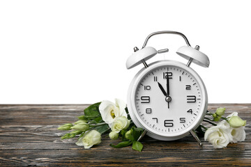 Alarm clock and beautiful eustoma flowers on wooden table against white background