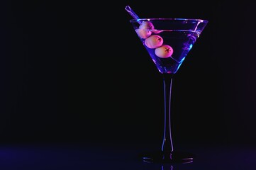Martini glass and olives on a black background with neon lights