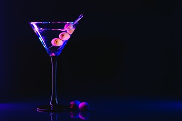 Martini glass and olives on a black background with neon lights