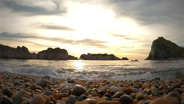 Lulworth Cove sunset. Wave covering the beach