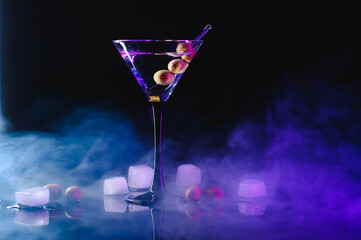 Martini glass and olives on a black background with neon lights