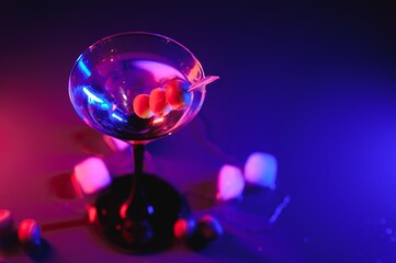 Martini glass and olives on a black background with neon lights