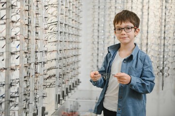 boy choosing glasses in optics store.