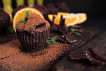 Chocolate muffin sprinkled with cocoa on a wooden support, laid on a wooden table. Chocolate muffin...