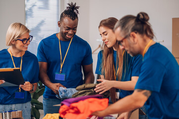 Diverse volunteers working in a charity donation center and packing clothes and food