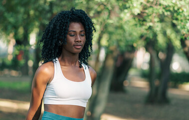 bella mujer afroamericana joven con afro sonriendo feliz después de estirar en el entrenamiento.