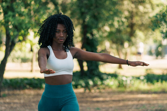 bella mujer afroamericana crespa con ropa de ejercicio prepar&aacute;ndose y estirando para hacer ejercicios