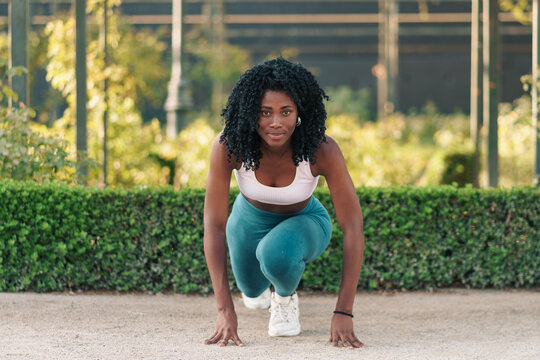 bella mujer negra haciendo ejercicios al aire libre, haciendo estiramientos y preparándose para correr.