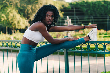 bella mujer negra estirando y calentando para hacer deportes, salir a correr al aire libre en un parque en verano en un día soleado. - obrazy, fototapety, plakaty