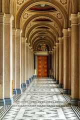 Obraz premium A corridor of white columns and high ceilings, with a door at the end. Architecture, old