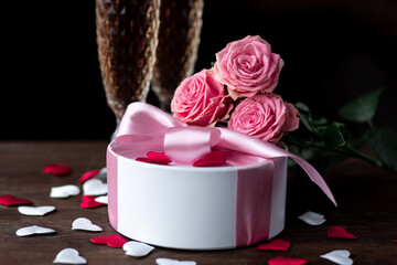 Obraz na płótnie Canvas Beautiful surprise greeting for saint Valentine's or Women's Day, birthday or Anniversary for beloved. Fresh pink roses, gift box with sweets. Dark background. Holiday atmosphere