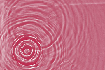 Abstract water texture, surface with drops, rings and ripple. Flat lay view, background with copy space.  Viva Magenta color of the year 2023