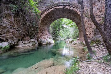 old bridge over the river, with green water from the stones. 