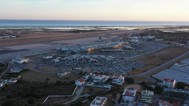 Aerial view of Portuguese Faro Airport, airplanes and runways against the sea. On the Sunset.