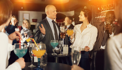 Positive man and woman drinking alcohol and having conversation on corporate party