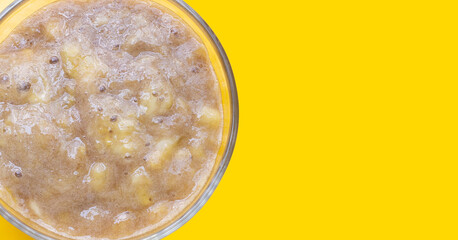 Mashed Bananas in white bowl on yellow background.