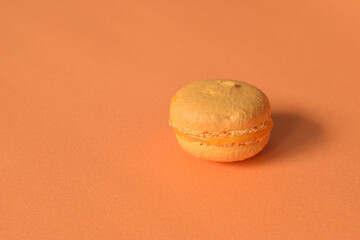 An orange macaron on a minimalistic orange background
