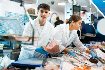 Male seller demonstrates large piece of tuna fillet at the fish market