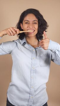 vertical video of young latina woman showing how is tooth brushing, dental health.