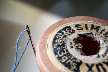 Aguja en carretel de hilo antiguo fotografía macro