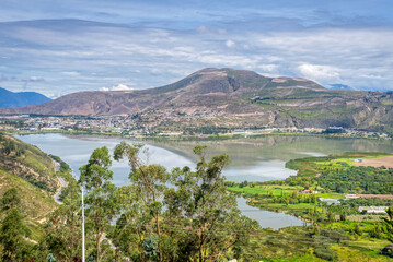 High view of the Yahuarcocha lake and surrounding trees and mountains, part of the Ecuadorian...