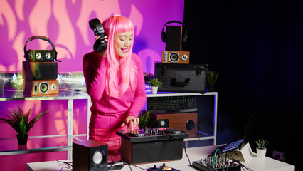 Musician playing techno song using professional turntables, enjoying performing music in night club. Performer using cutting-edge technology to remix music, having fun playing song