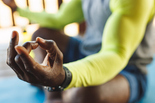 Close-up of african american senior man's hand in mudra position meditating in log cabin - Powered by Adobe