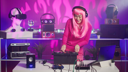 Musician with headset standing at dj table having fun while mixing stereo sounds with electronics. Cheerful performer enjoying to play music using professional mixer console in nightclub