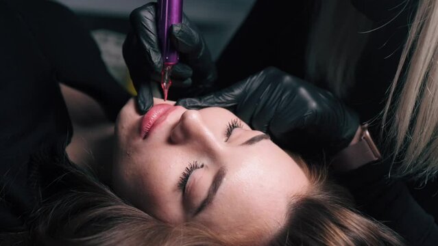 Permanent lip makeup. The cosmetologist makes the procedure of permanent makeup to the client in the salon. Close up.