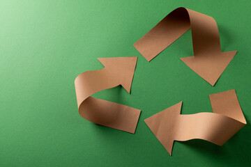 Close up of recycling symbol of paper arrows on green background with copy space