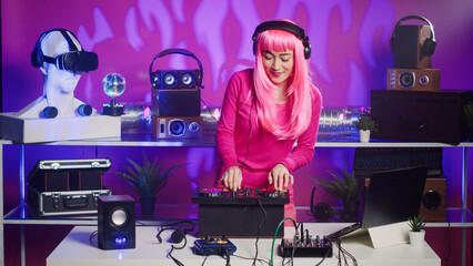 Cheeful artist standing at dj table playing electronic music using professional mixer console,...