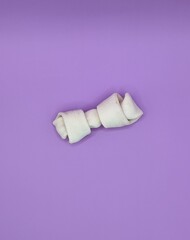 A white treat bone for dog on purple background