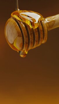 honey dripping from a wooden dipper .vertical clip 4k 