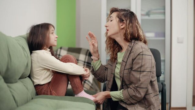 Woman Psychologist communicates with a girl in the office. The doctor provides psychological assistance to a depressed child.