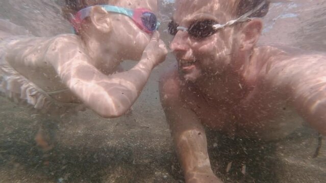 Young Girl Diving with Father in Mediterranean Sea Water in Swimming Glasses