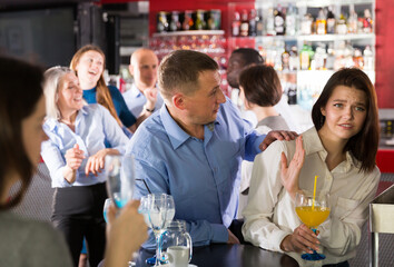 Tipsy man trying to seduce young female colleague on office party at nightclub..