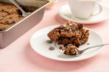 Close up brownies with chocolate chips and rolled oats served with cup of tea on pink background
