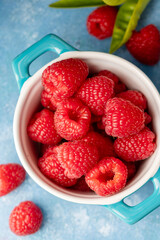 Closeup raspberry fruits in blue bowl, blue background