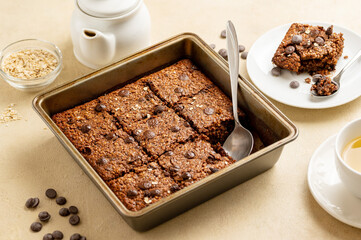 Close up brownies with chocolate chips and rolled oats served with cup of tea