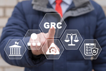 Businessman using virtual touch screen presses abbreviation: GRC. GRC Governance Risk and...