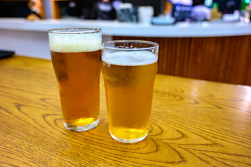 Fresh draught lager or IPA beer is glass served in indoor cafe close up, pint of beer