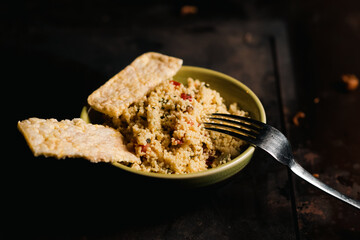 Rice bread and tomato and spice couscous salad on a dark background. Tabbouleh salad.