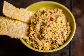 Rice bread and tomato and spice couscous salad on a dark background. Tabbouleh salad. Close-up.