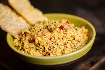 Rice bread and tomato and spice couscous salad on a dark background. Tabbouleh salad. Close-up.