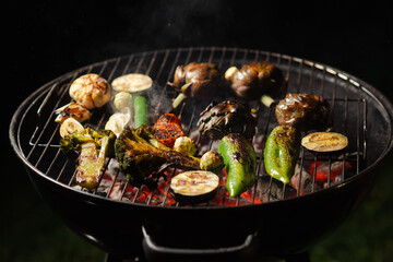 Green grilling. Various vegetables - artichokes, peppers, eggplants are grilled. Proper, vegan nutrition. Dark background. Red coals.