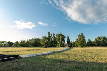 Nylon material of a white hot air balloon stretched out on a green meadow