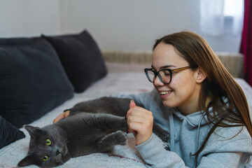 A young girl is playing with her cat at home during the day