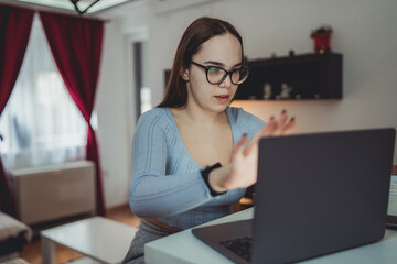 A young girl is studying or doing business from home on her laptop