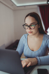 A young girl is studying or doing business from home on her laptop